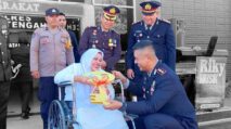 Kapolres Aceh Tengah menyerahkan simbol kunci rumah kepada ibu penyandang disabilitas yang duduk di kursi roda saat peringatan Hari Bhayangkara ke-79.