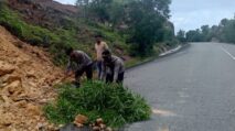 Petugas Polsek Sampoiniet bersama warga membersihkan material longsor yang menutupi badan jalan di Gunung Keumala, Aceh Jaya